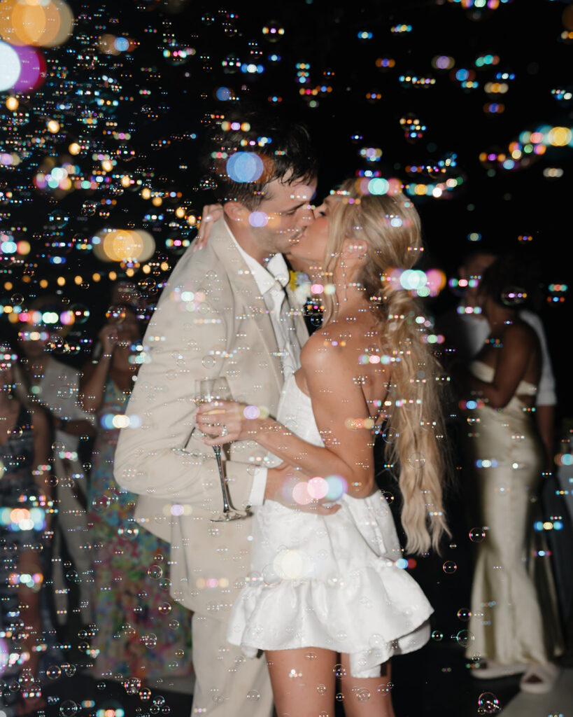 bride and groom kiss while bubbles surround them