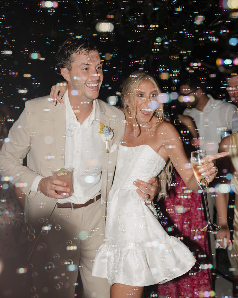 bride and groom kiss while bubbles surround them