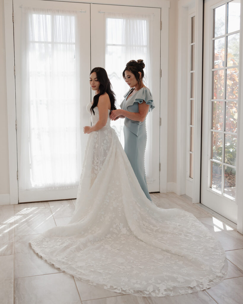 mother of the bride helps bride into her Galia Lahav wedding gown