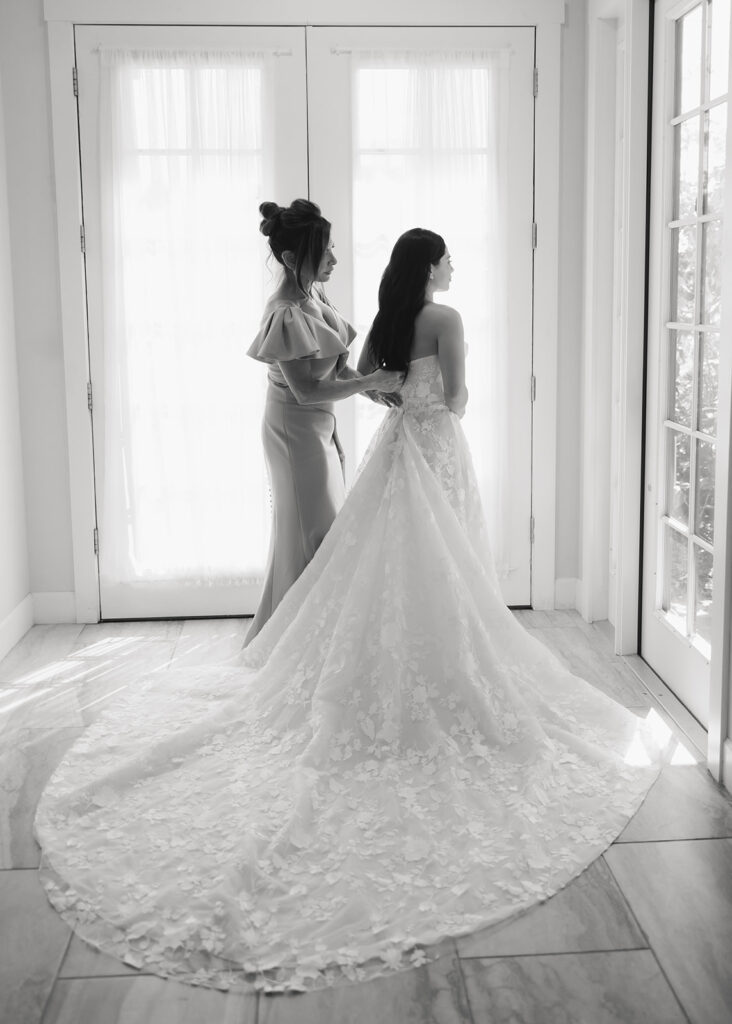 mother of the bride helps bride into her Galia Lahav wedding gown