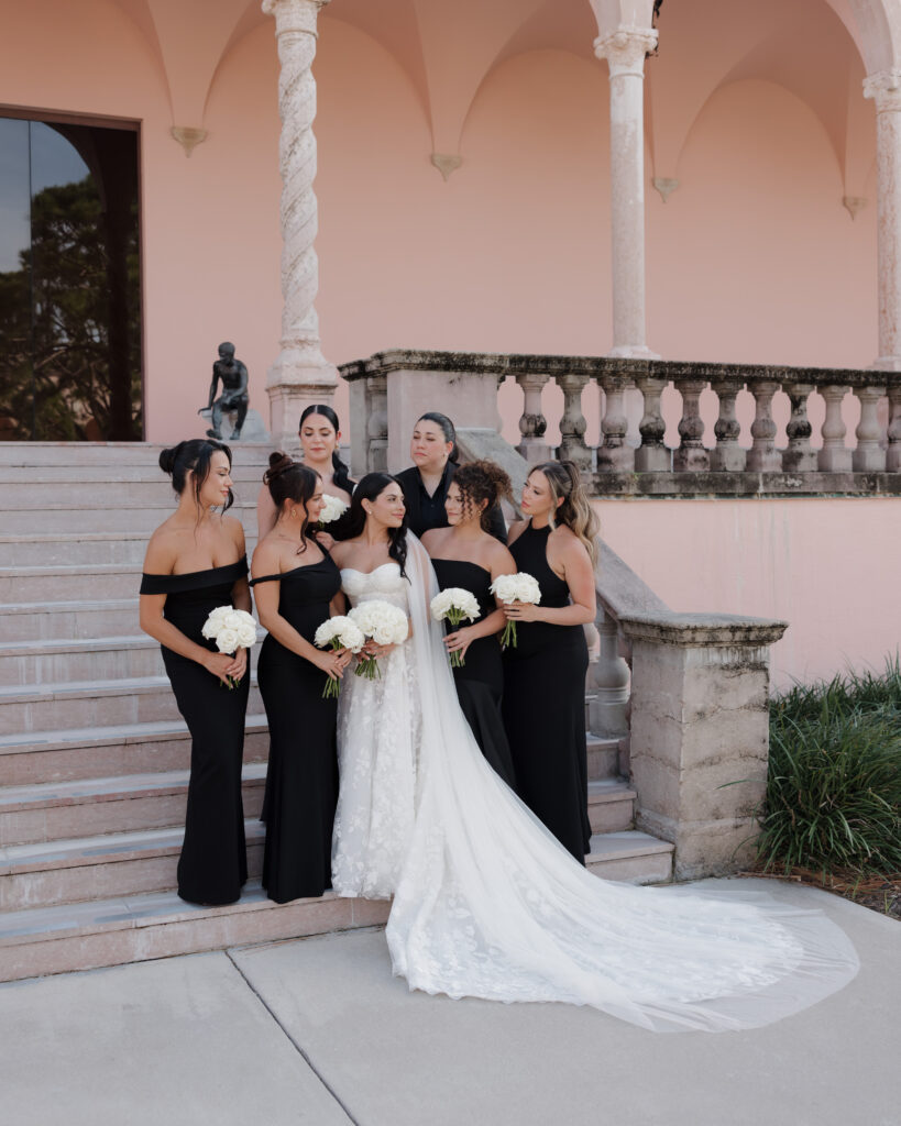 bride and bridesmaids stand on the steps of the Ringling courtyard