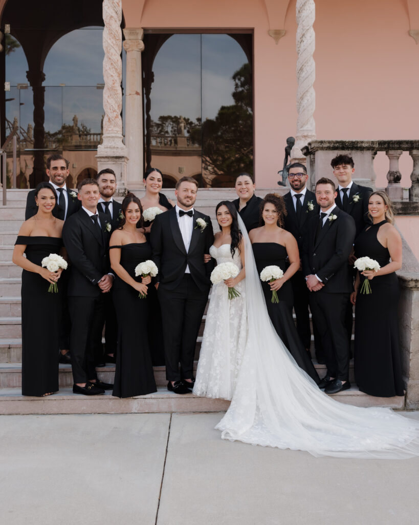 bride, groom, and their wedding party stand on the steps leading to the Ringling