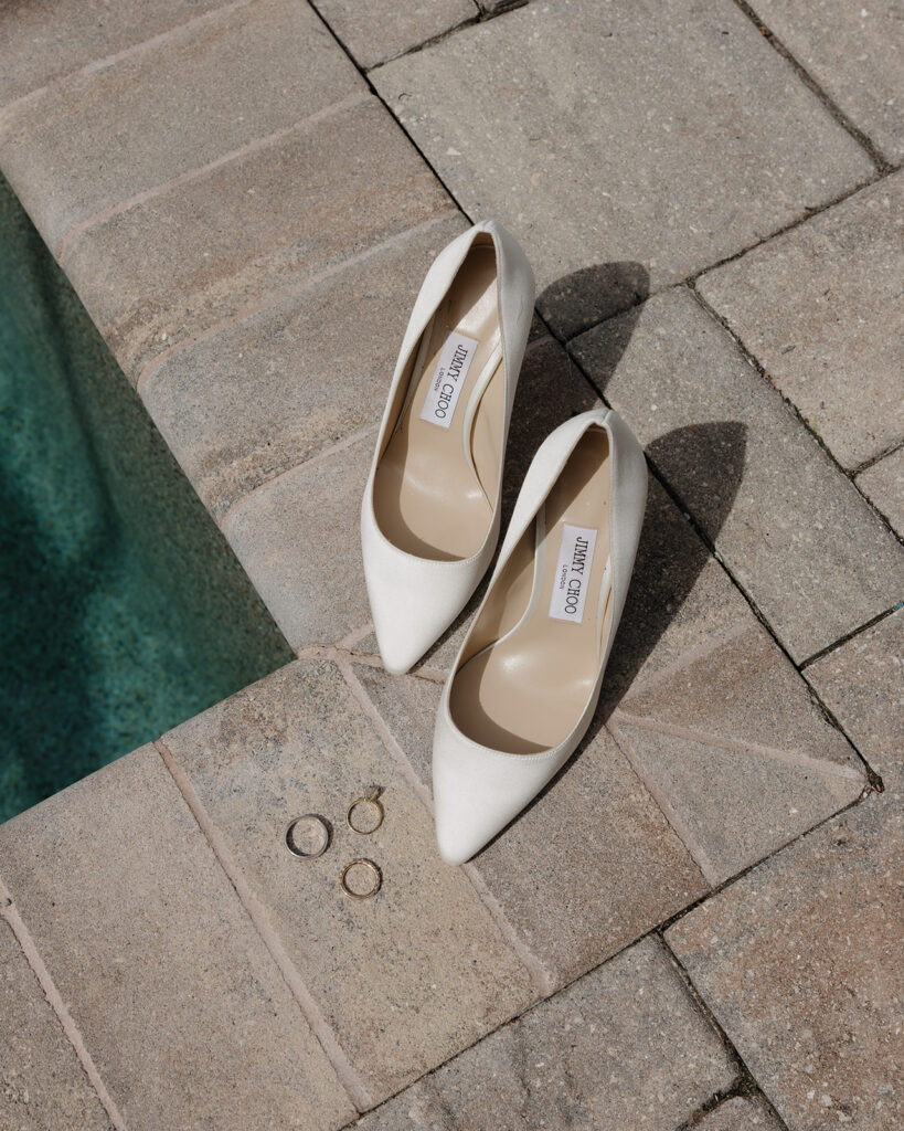 Jimmy Choo heels lay next to a pool