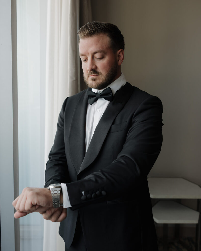 The groom straightens his watch at the Westin Hotel