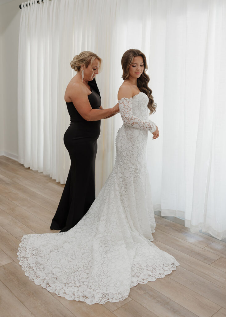 mother of the bride helps bride into wedding dress