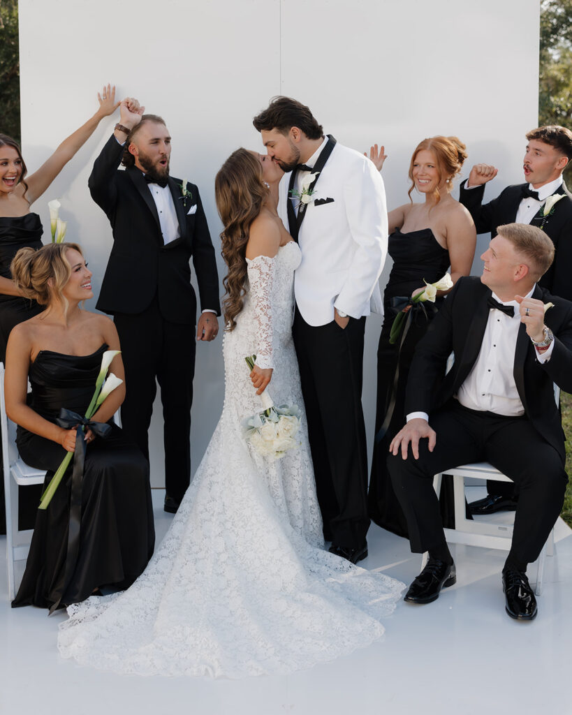 bride and groom kiss as bridesmaids and groomsmen cheer