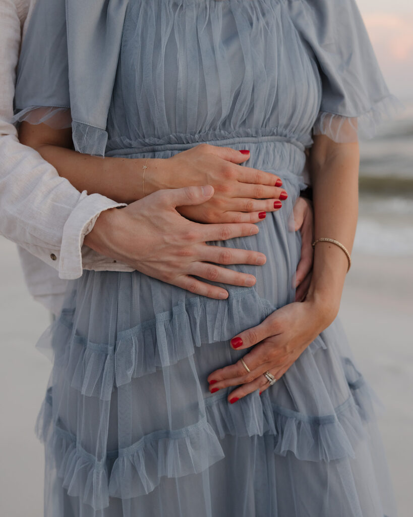 man and woman hold baby bump