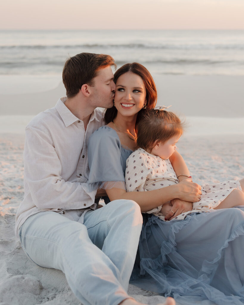 Family of three snuggle on the beach