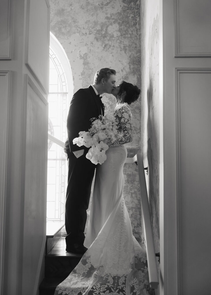 bride and groom kiss on a staircase