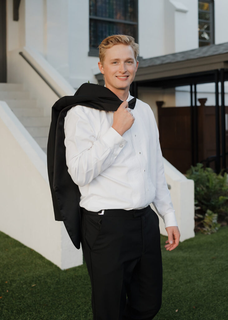 groom walks with his jacket over his shoulder