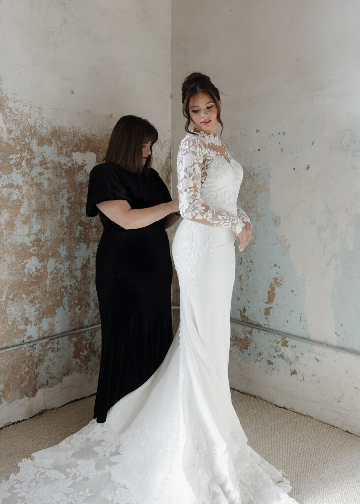 mother helps daughter into wedding dress