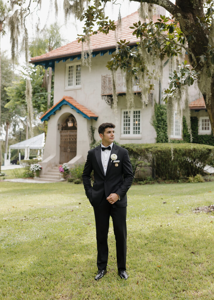 groom stands outside of Sydonie Mansion
